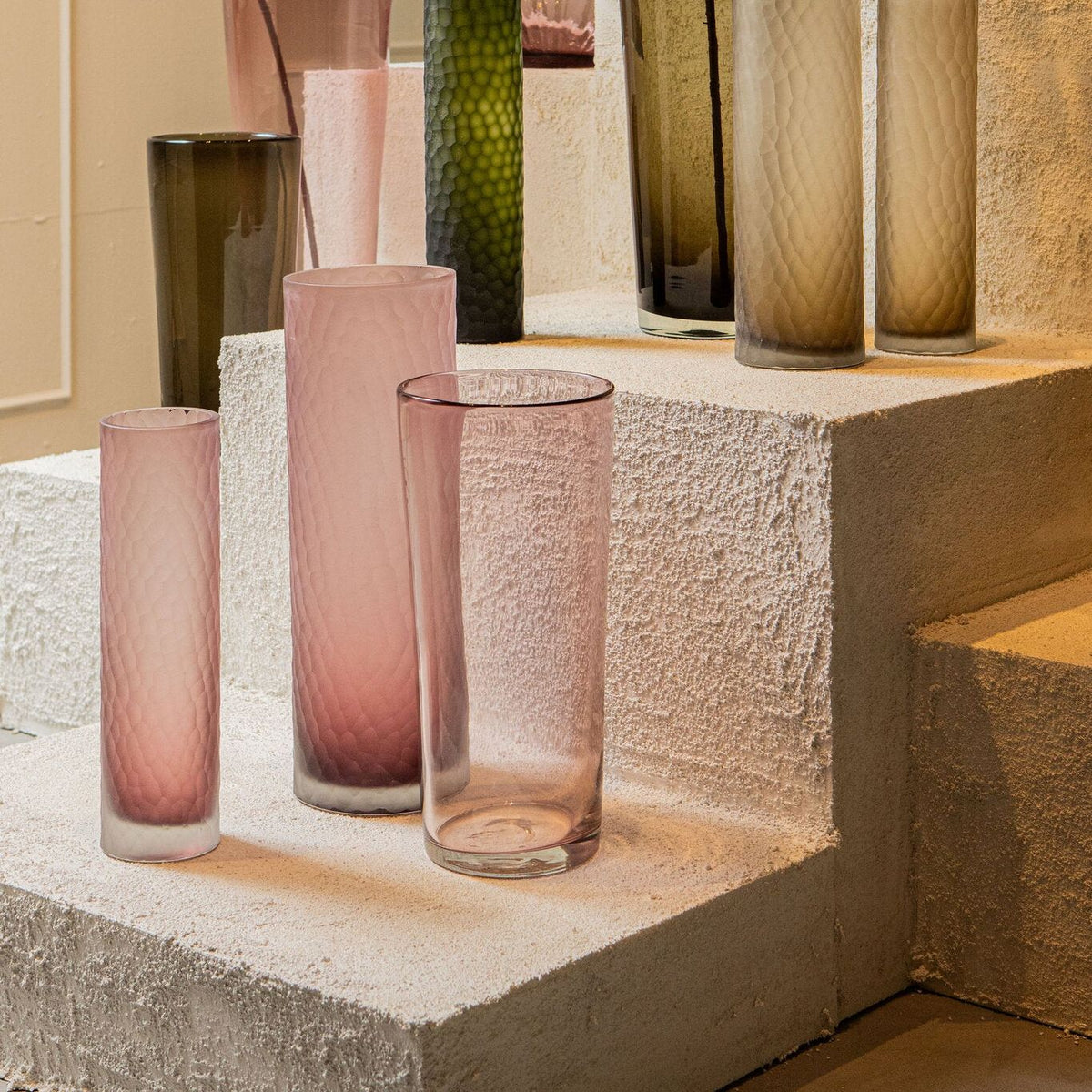 Mehran vaas van PTMD in een woonsetting, roze glazen vaas met takken