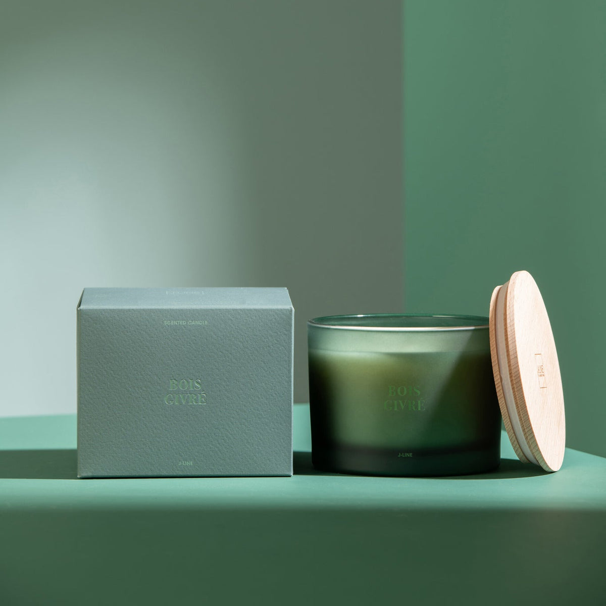 Geurkaars Accords Essentiels Bois Givré 28 Uur van J-Line met bijpassende doos in een sfeervolle groene setting