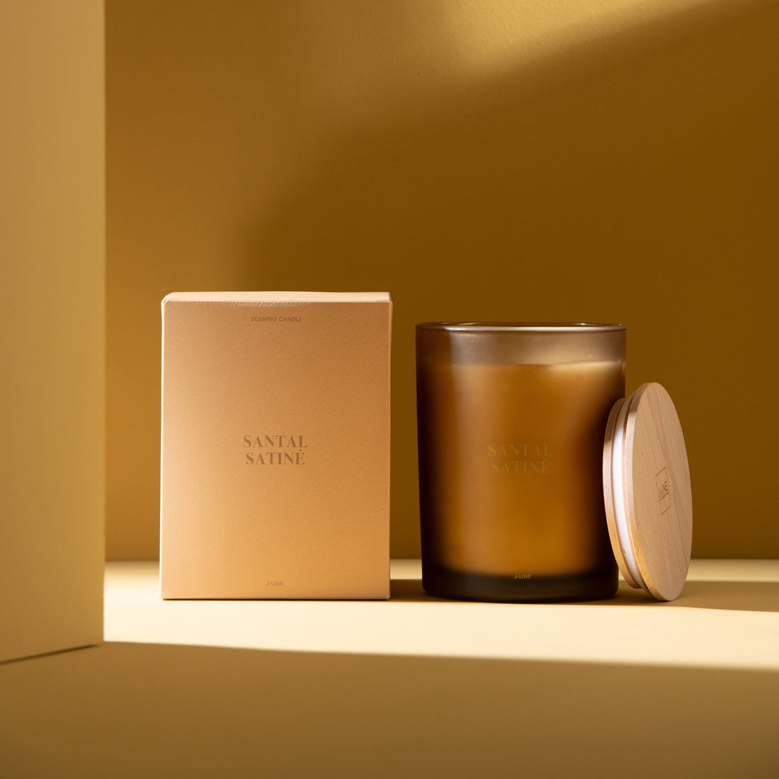 Geurkaars Accords Essentiels Santal Satiné 52 Uur van J-Line met bijpassende doos in een sfeervolle gele setting
