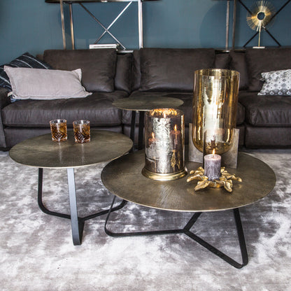 Kae salontafels van PTMD in goud aluminium in drie formaten samen gestyled op een grijs vloerkleed
